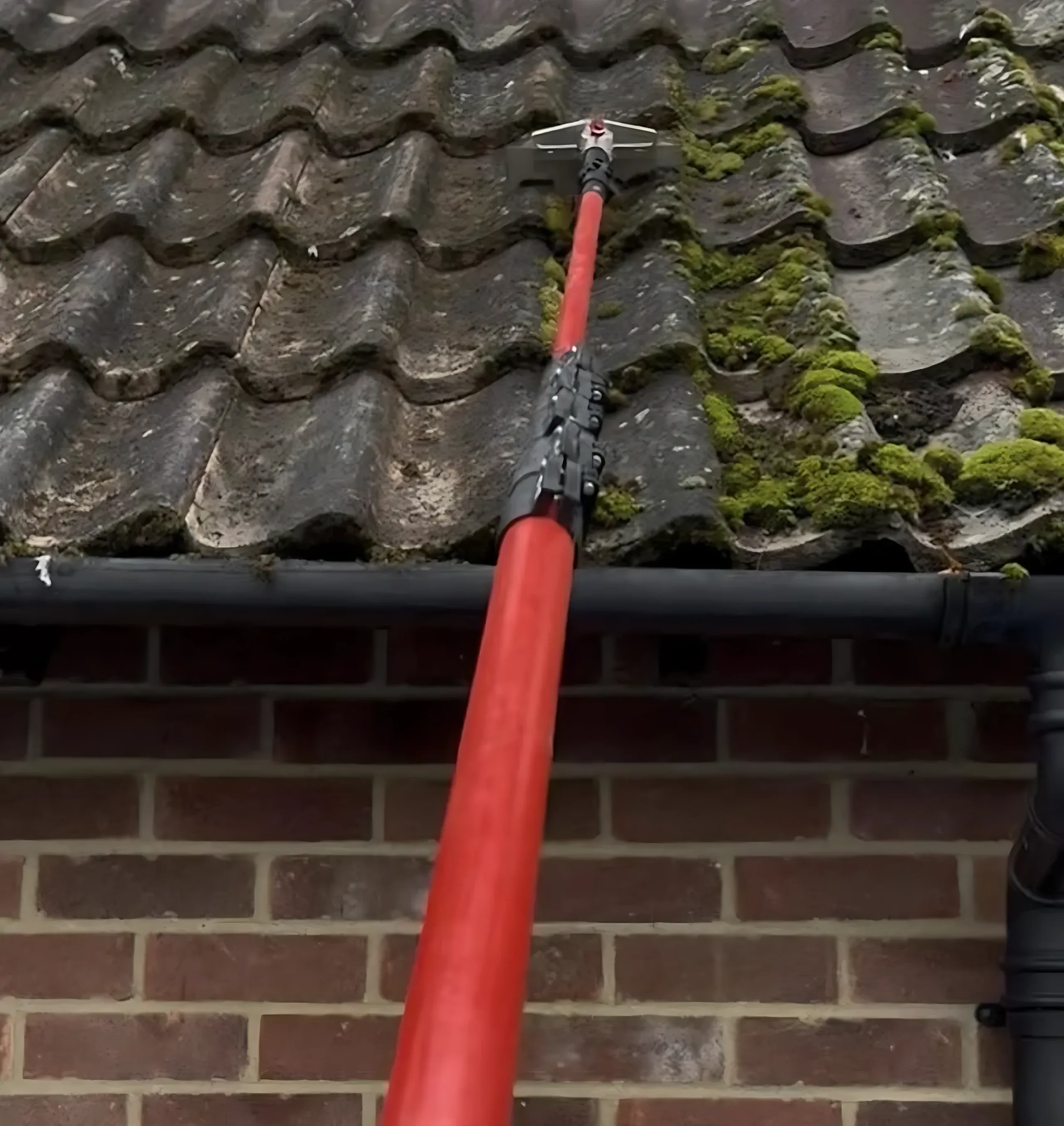 Moss being cleared from the roof edge above a gutter