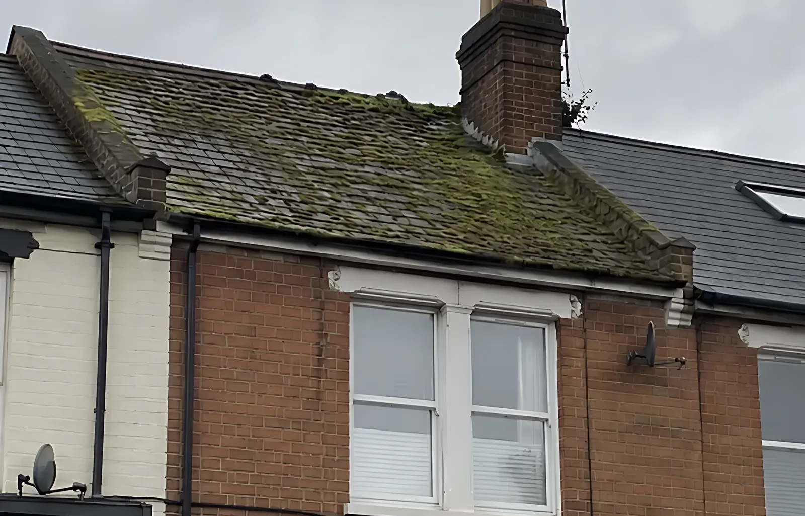 The same roof covered in moss with a blocked gutter